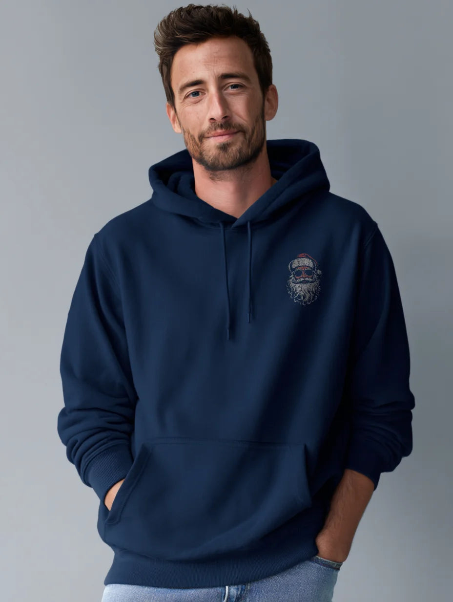 Navy men’s hoodie with small vintage Santa face and sunglasses chest print, modeled by a man standing in a studio with a gray background, hands in the front pocket.