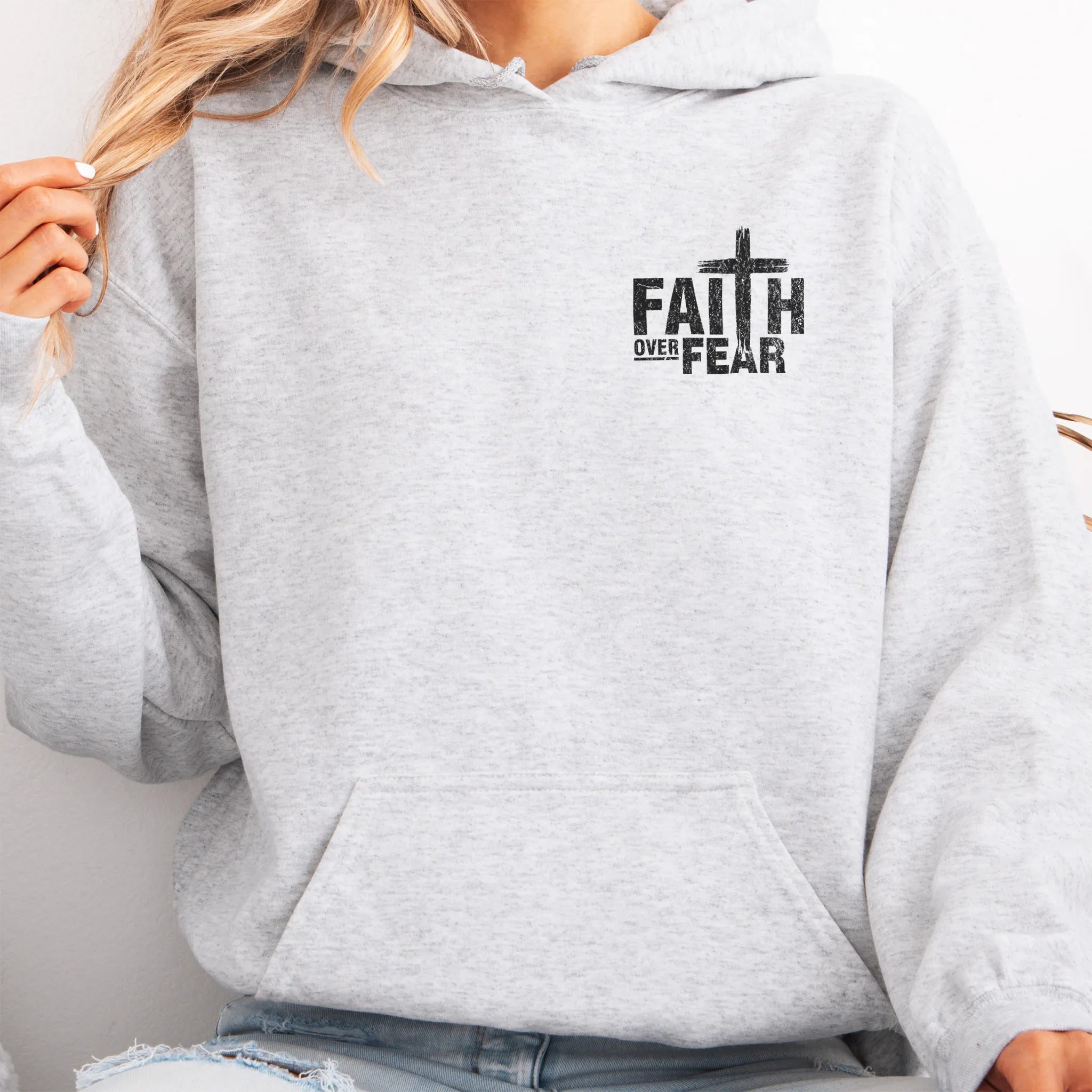 Ash Oakley June hoodie, left chest badge reads Faith Over Fear with small cross, kangaroo pocket and relaxed modern fit, studio front view