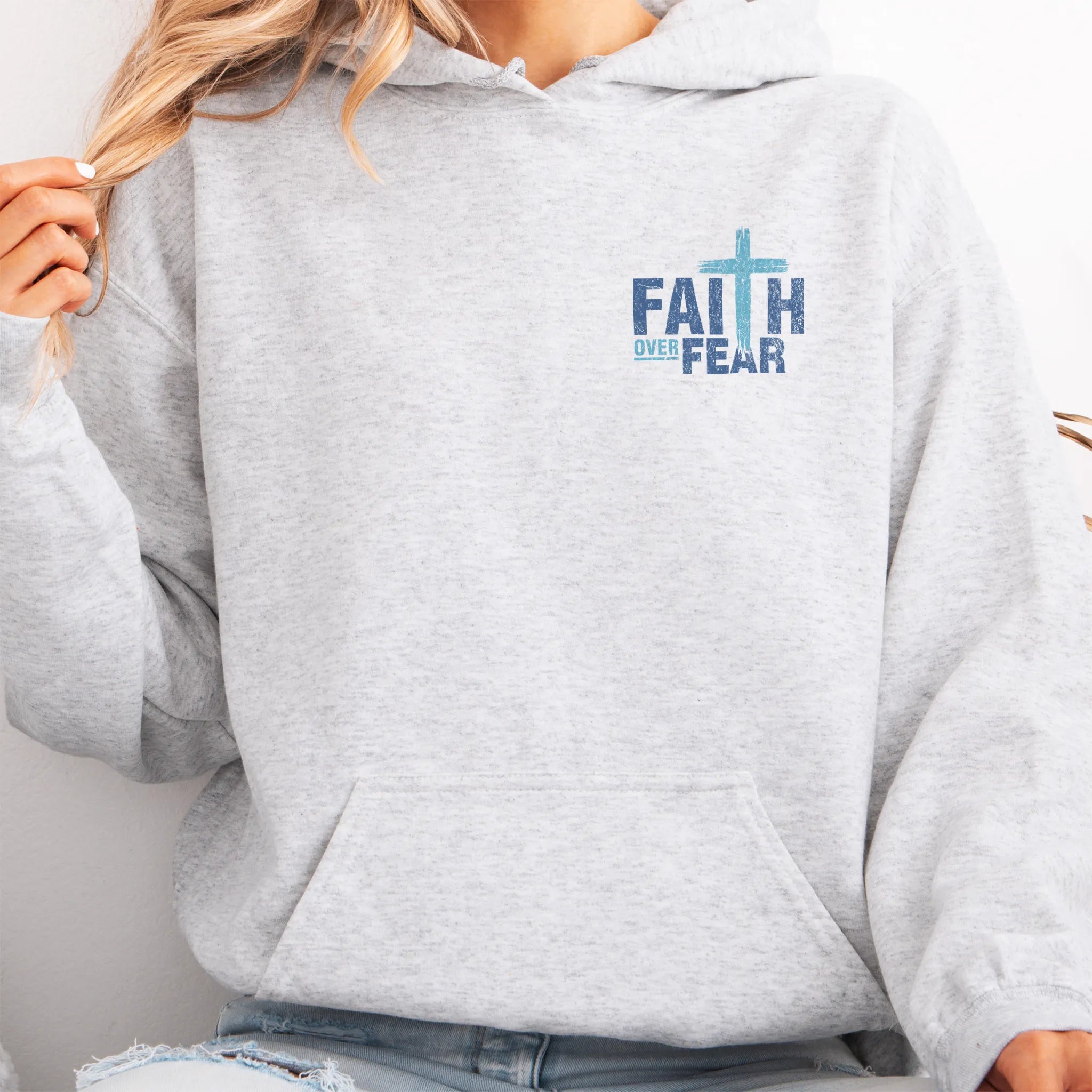 Ash Oakley June hoodie, left chest badge reads Faith Over Fear with small cross, kangaroo pocket and relaxed modern fit, studio front view