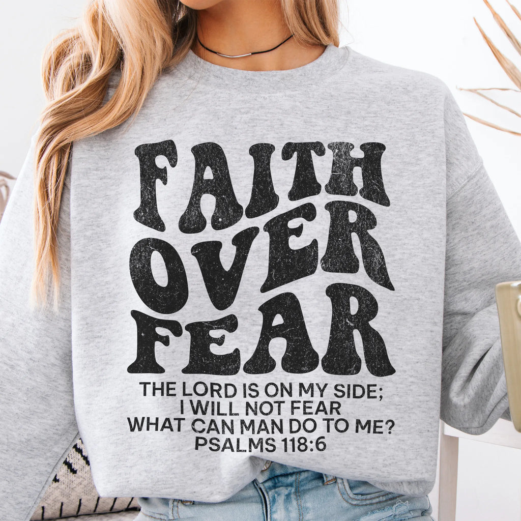 Ash Oakley June sweatshirt, large front lettering reads Faith Over Fear with supporting lines The Lord Is On My Side I Will Not Fear What Can Man Do To Me, studio front view