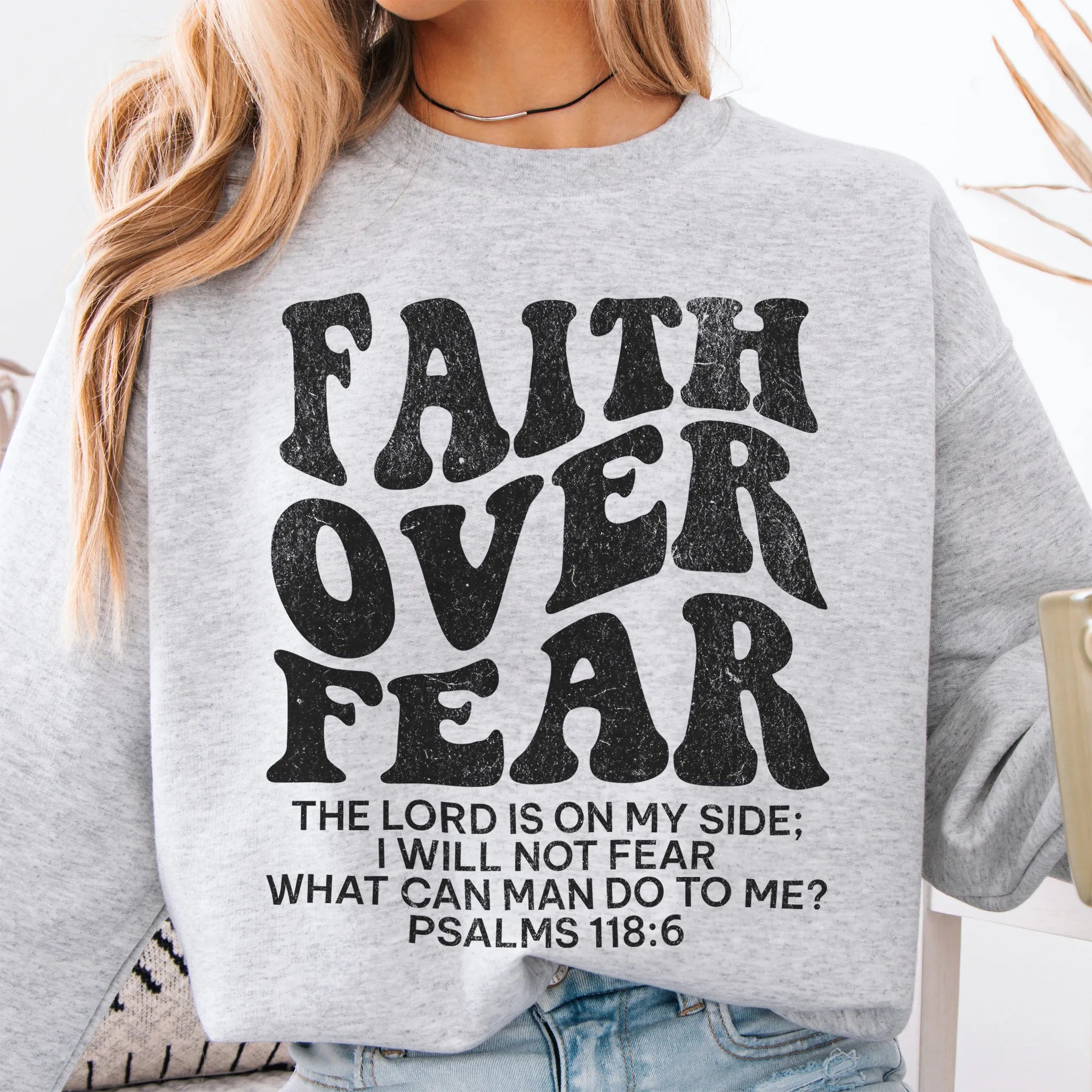 Ash Oakley June sweatshirt, large front lettering reads Faith Over Fear with supporting lines The Lord Is On My Side I Will Not Fear What Can Man Do To Me, studio front view