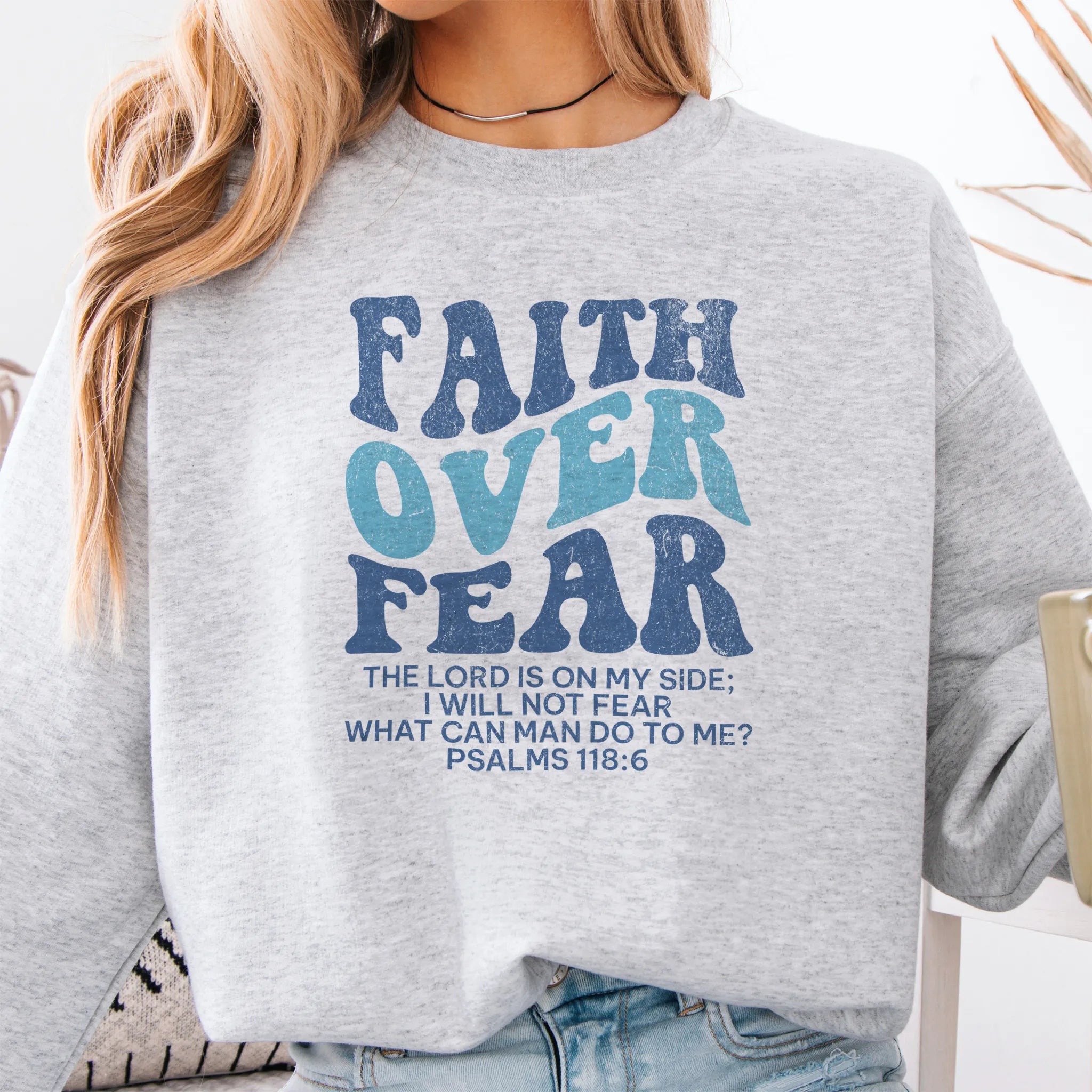 Ash Oakley June sweatshirt, large front lettering reads Faith Over Fear with supporting lines The Lord Is On My Side I Will Not Fear What Can Man Do To Me, studio front view