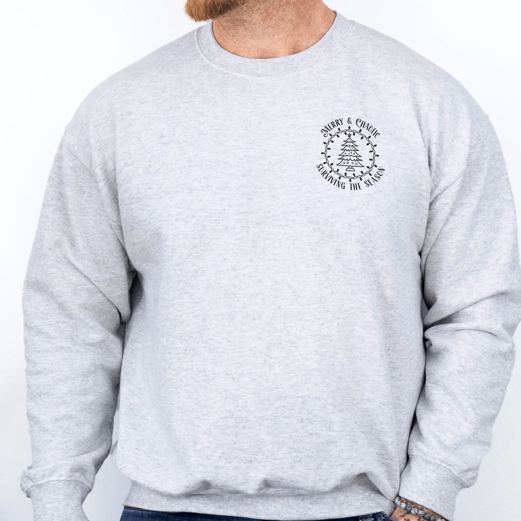 Ash men’s sweatshirt left chest badge text “Merry & Chaotic — Surviving the Season”