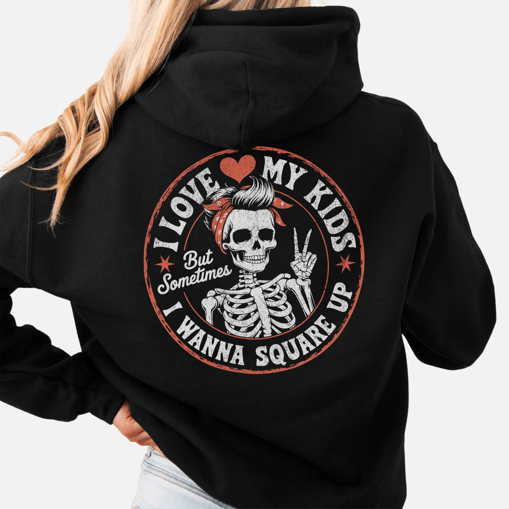 Black Oakley June hoodie, large back circle graphic with skeleton mom giving a peace sign, text reads I Love My Kids But Sometimes I Wanna Square Up, studio back view