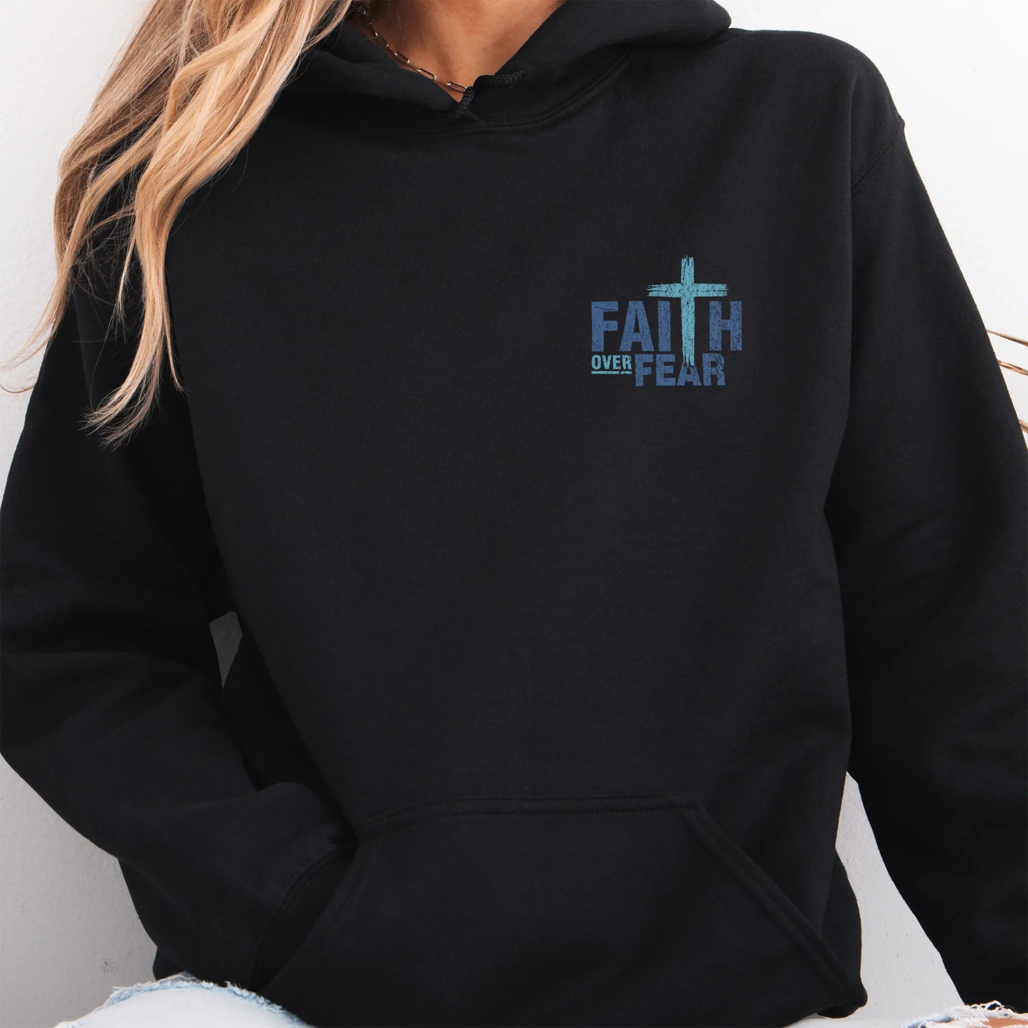 Black Oakley June hoodie, left chest badge reads Faith Over Fear with small cross, kangaroo pocket and relaxed modern fit, studio front view