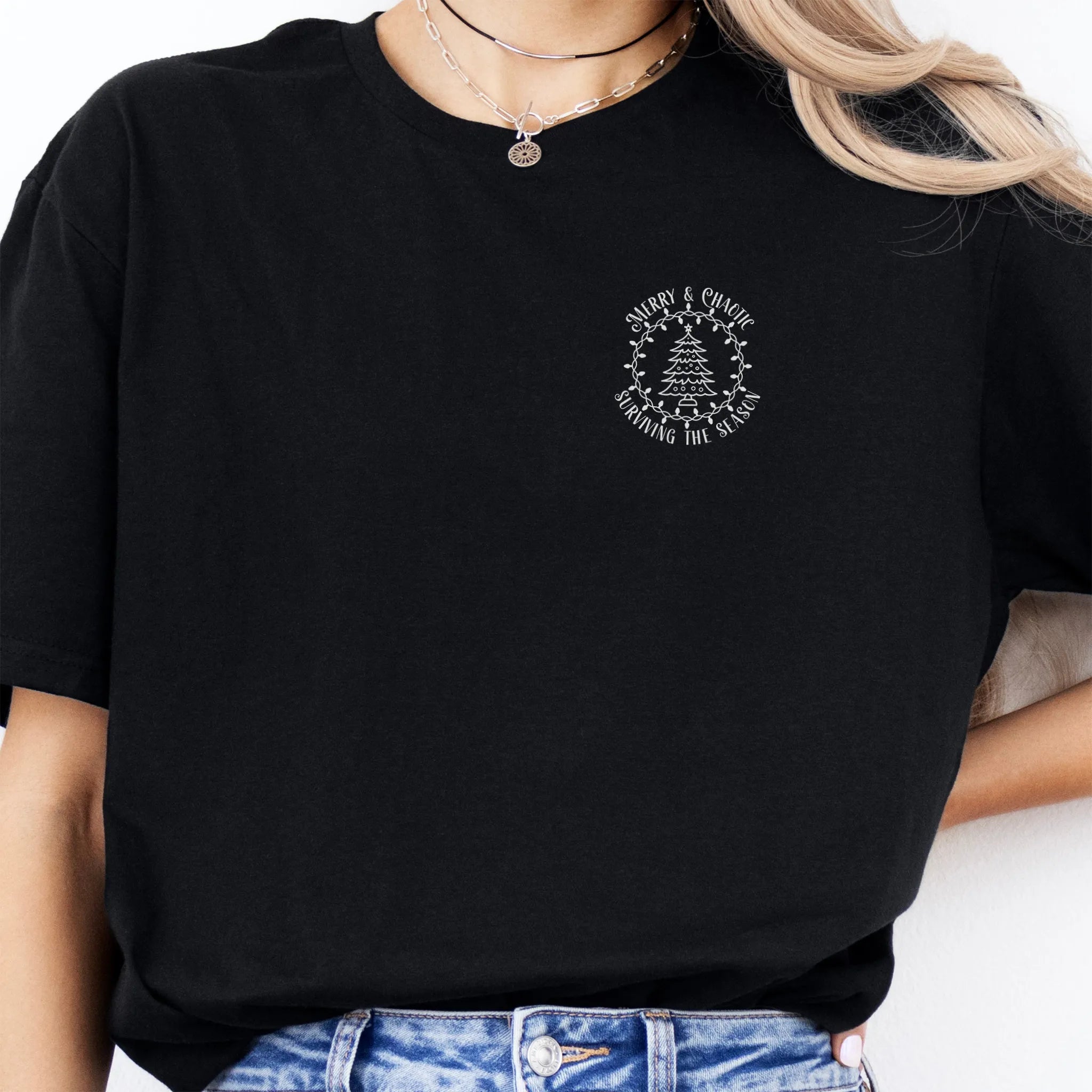 Black Oakley June tee left chest badge text “Merry & Chaotic — Surviving the Season” with Christmas tree