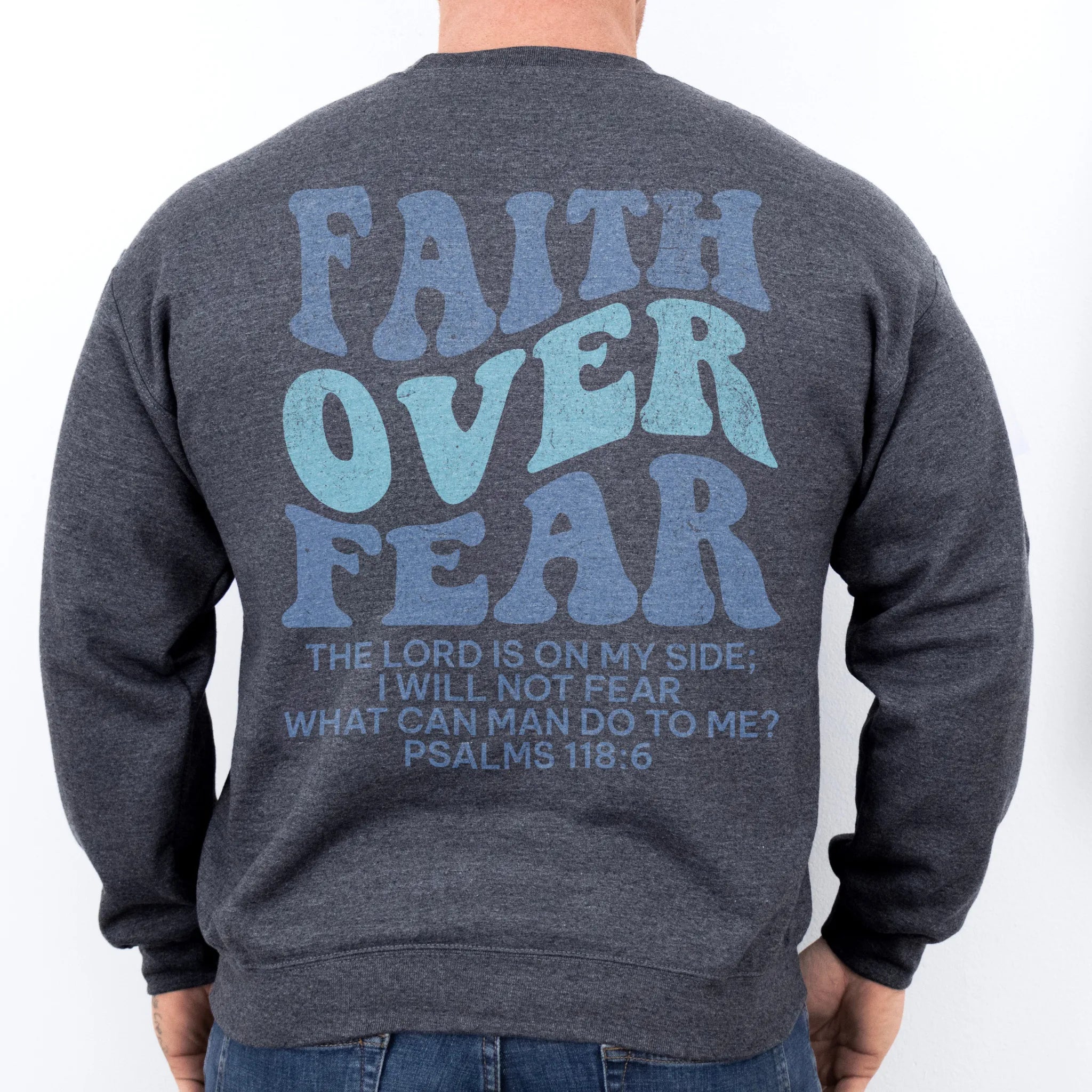 Dark Heather Oakley June sweatshirt, mens fit, large back lettering reads Faith Over Fear with supporting scripture lines, studio back view