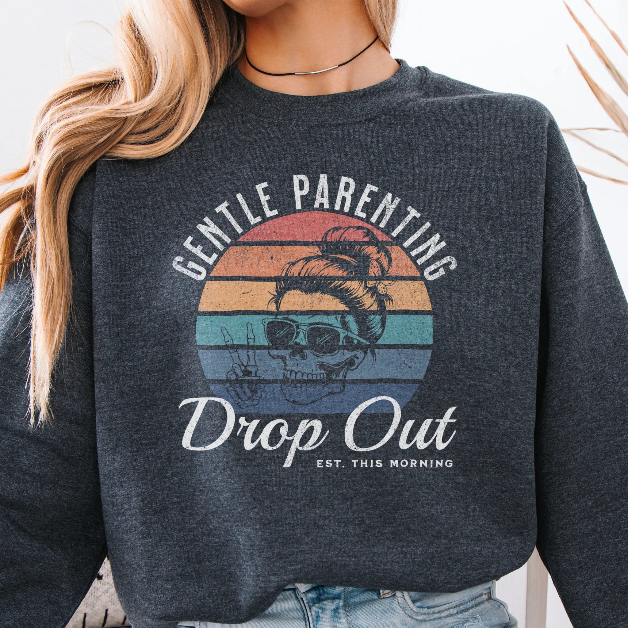 Dark Heather Oakley June Sweatshirt front view Gentle Parenting Drop Out large chest graphic skull with messy bun peace sign round retro stripe badge text Est This Morning distressed print