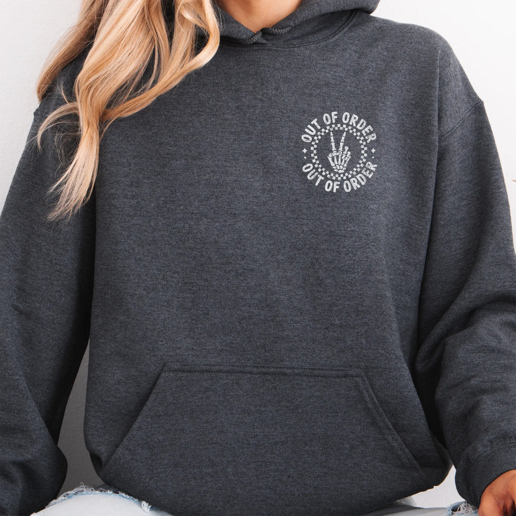 Dark Heather hoodie – left chest circular badge with “Out of Order” text, kangaroo pocket and relaxed modern fit, studio front view