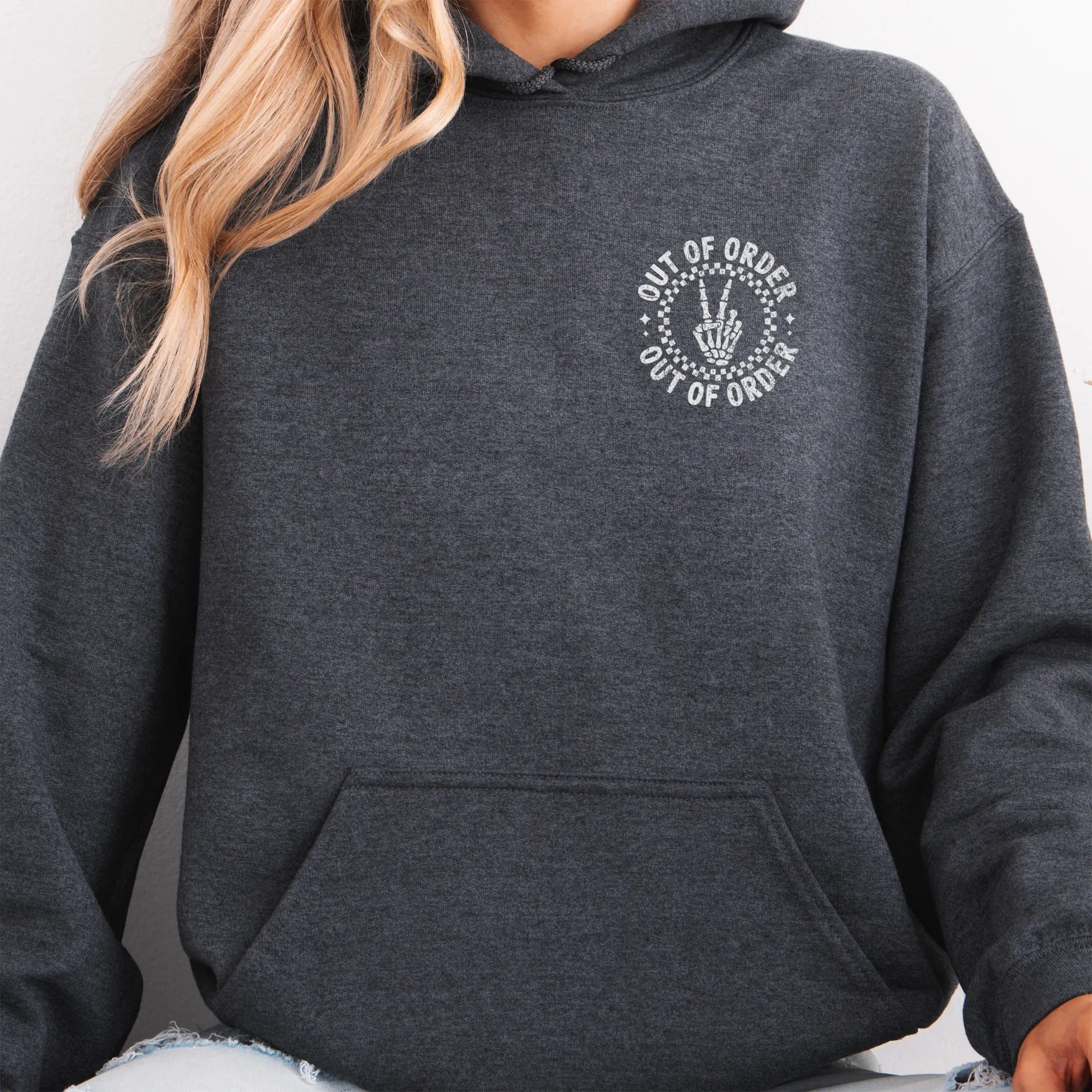 Dark Heather hoodie – left chest circular badge with “Out of Order” text, kangaroo pocket and relaxed modern fit, studio front view