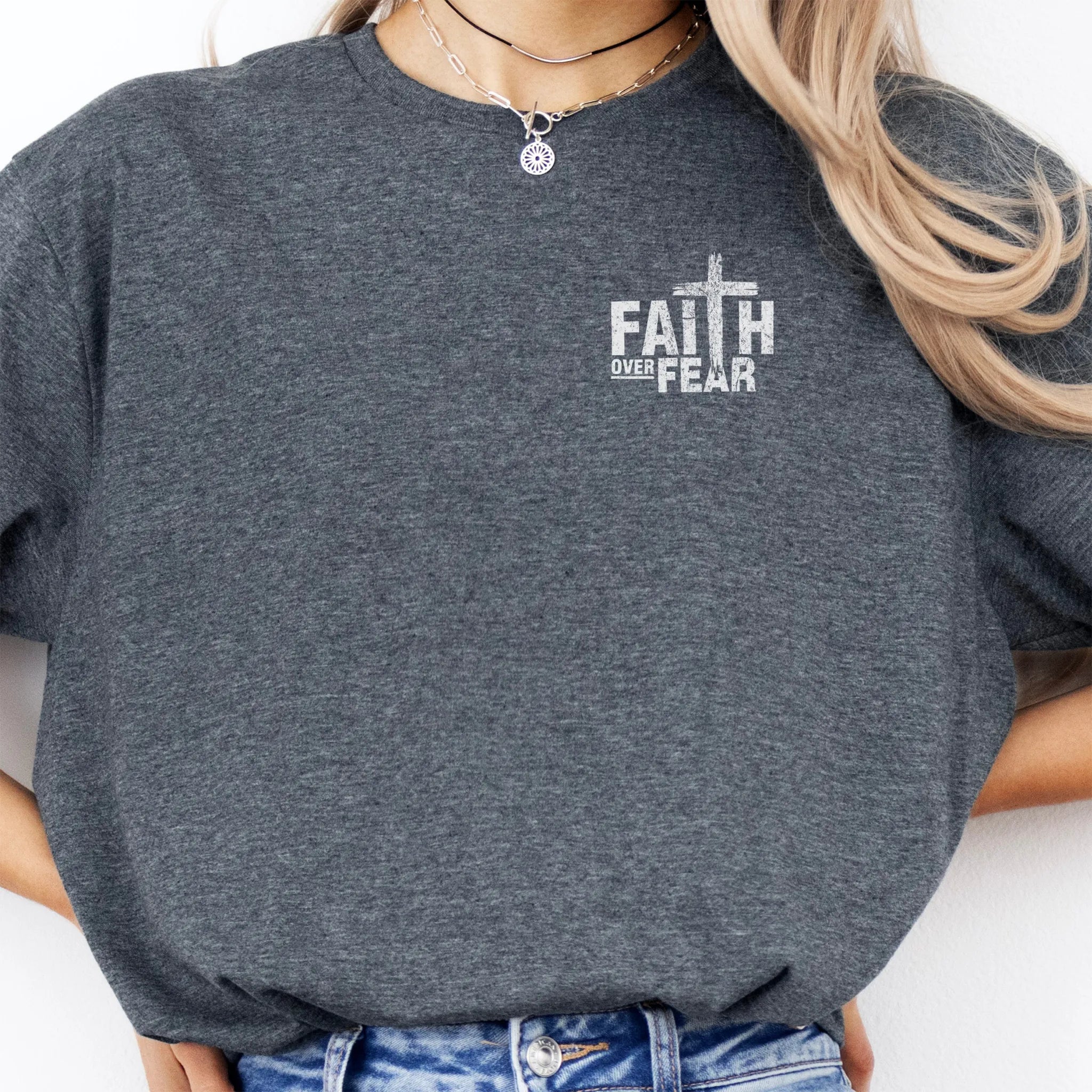 Dark Heather Oakley June t shirt, left chest badge reads Faith Over Fear with small cross, relaxed modern fit, studio front view