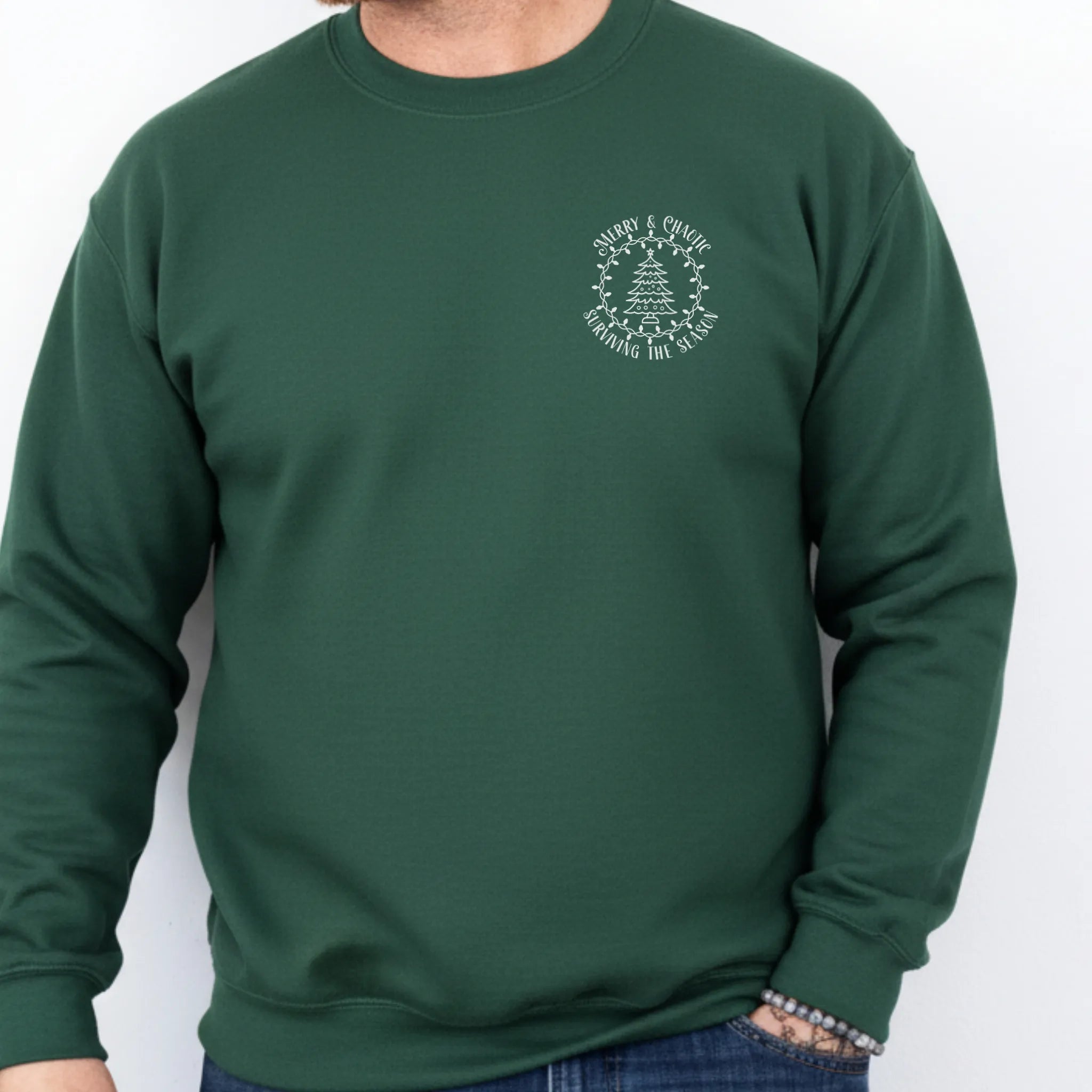 Forest Green men’s sweatshirt left chest badge text “Merry & Chaotic — Surviving the Season”