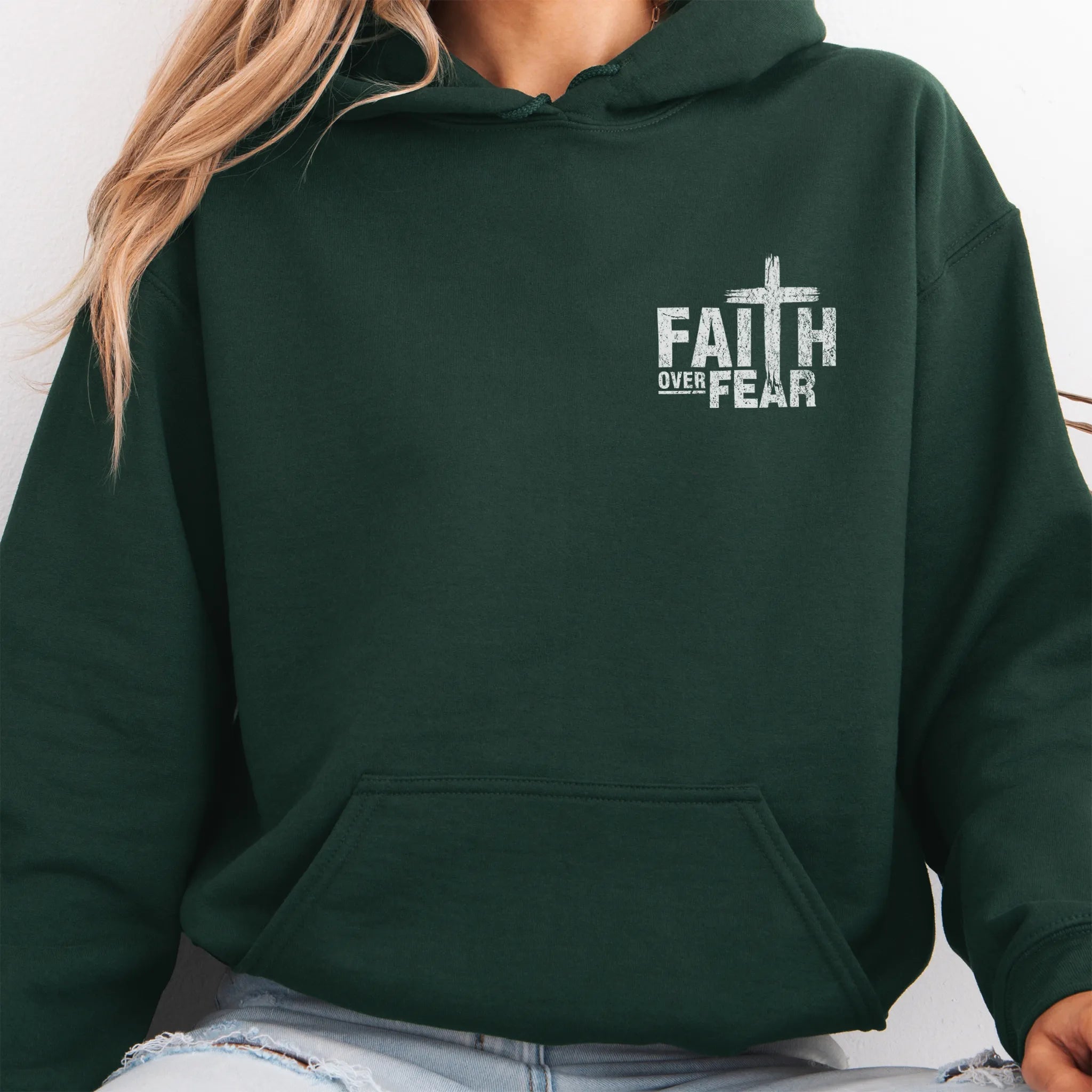 Forest Green Oakley June hoodie, left chest badge reads Faith Over Fear with small cross, kangaroo pocket and relaxed modern fit, studio front view