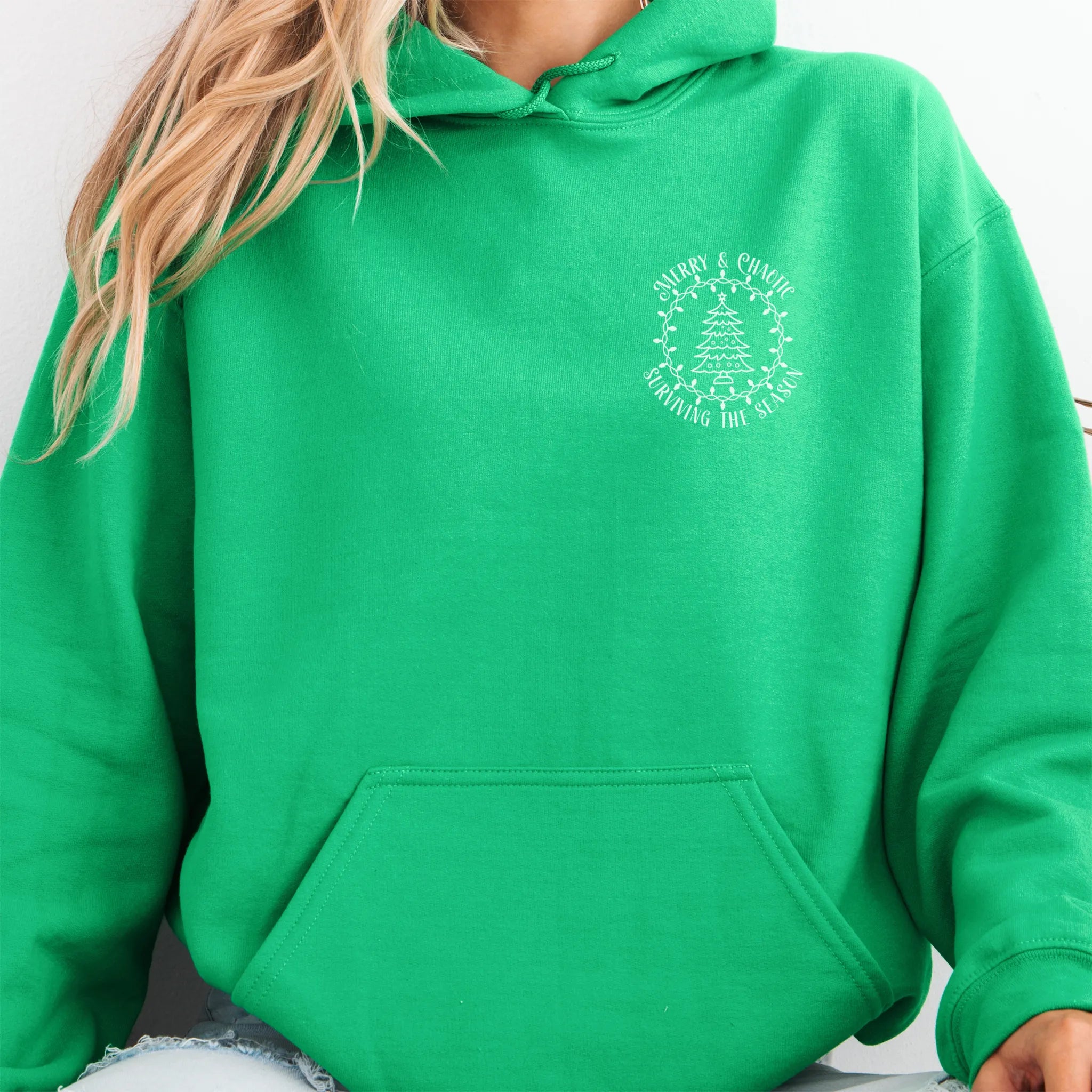 Irish Green women’s hoodie left chest badge text “Merry & Chaotic — Surviving the Season”