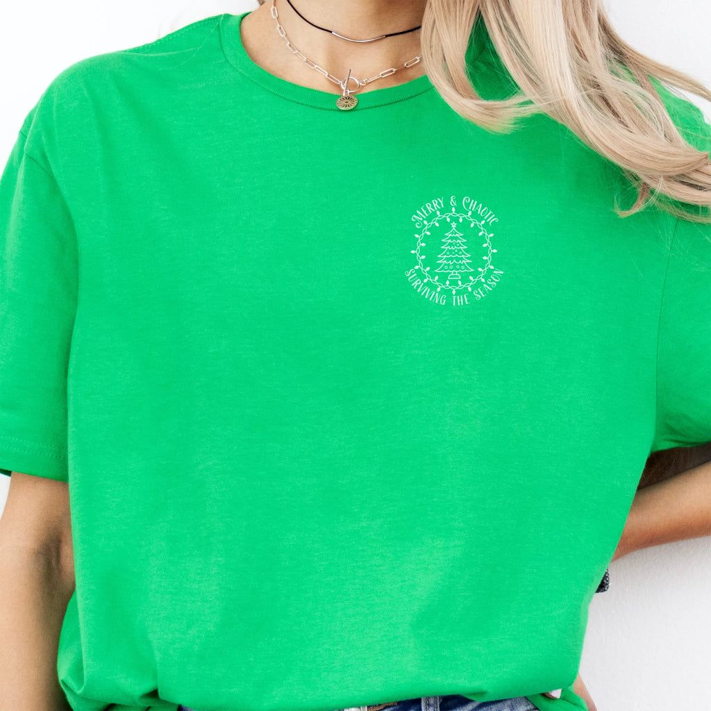 Irish Green Oakley June tee left chest badge text “Merry & Chaotic — Surviving the Season” with Christmas tree