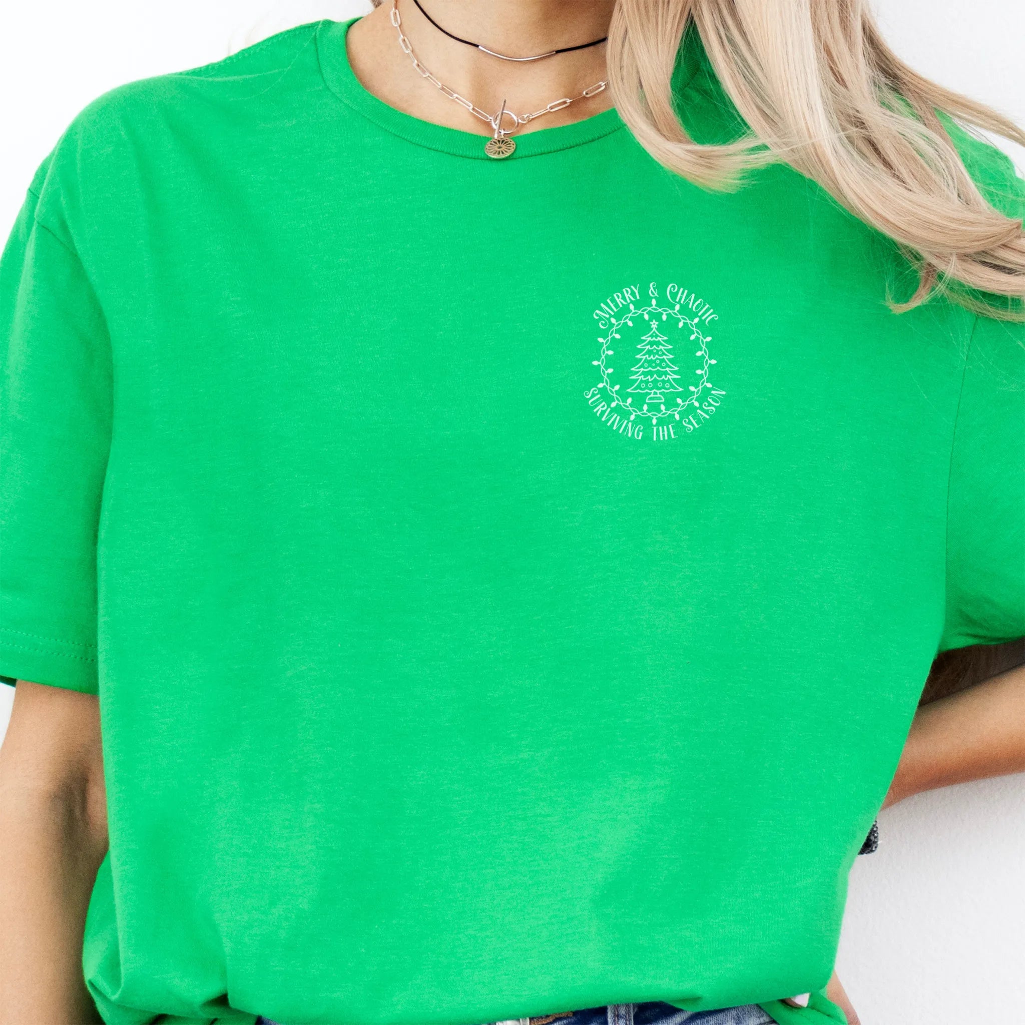 Irish Green Oakley June tee left chest badge text “Merry & Chaotic — Surviving the Season” with Christmas tree