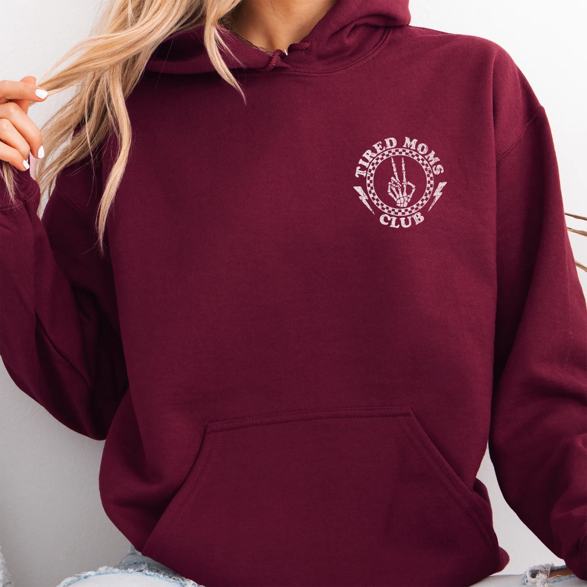 Maroon Oakley June Hoodie front view small left chest Tired Moms Club badge crest kangaroo pocket drawstrings visible distressed print
