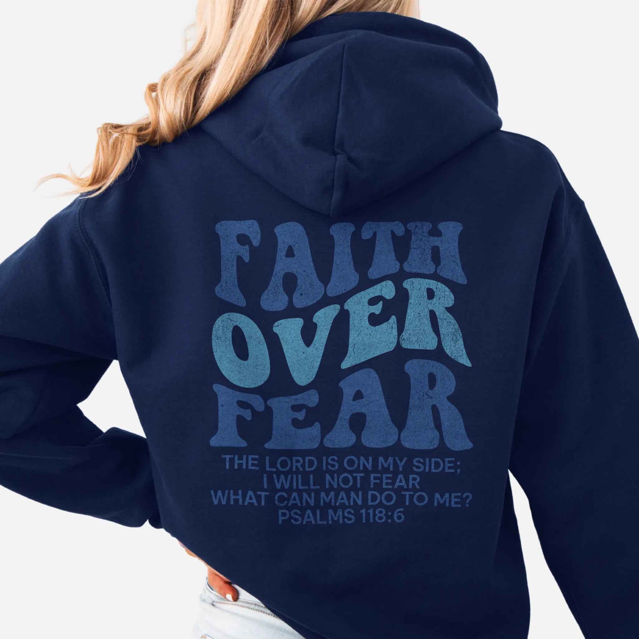 Navy Oakley June hoodie, large back lettering reads Faith Over Fear with supporting scripture lines, hood up, studio back view
