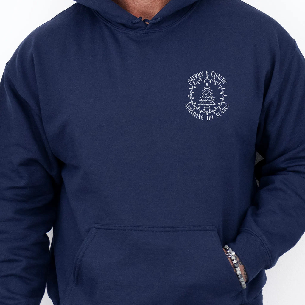 Navy men’s hoodie left chest badge text “Merry & Chaotic — Surviving the Season”