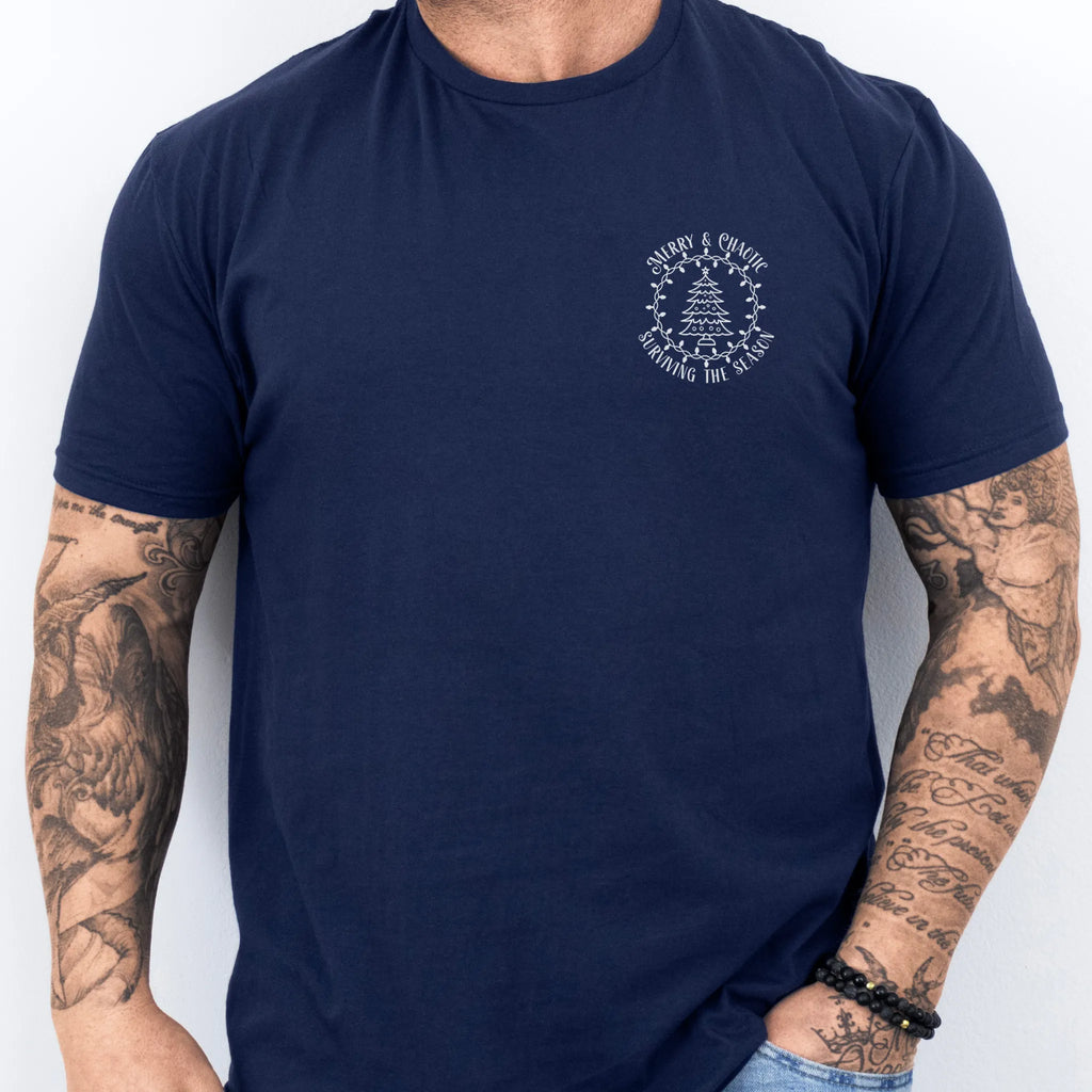 Navy Oakley June tee left chest badge text “Merry & Chaotic — Surviving the Season” with Christmas tree
