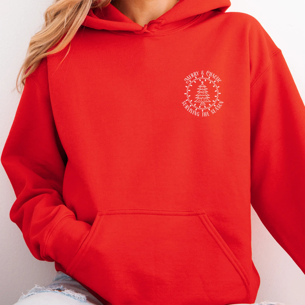 Red women’s hoodie left chest badge text “Merry & Chaotic — Surviving the Season”