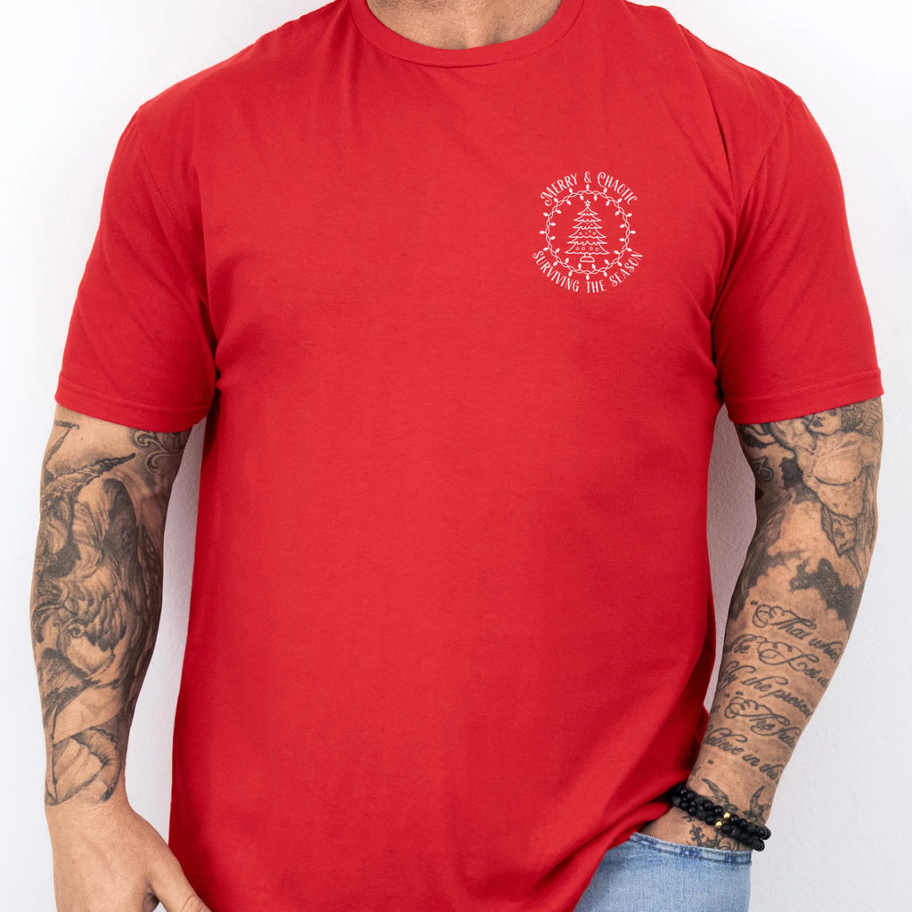 Red Oakley June tee left chest badge text “Merry & Chaotic — Surviving the Season” with Christmas tree