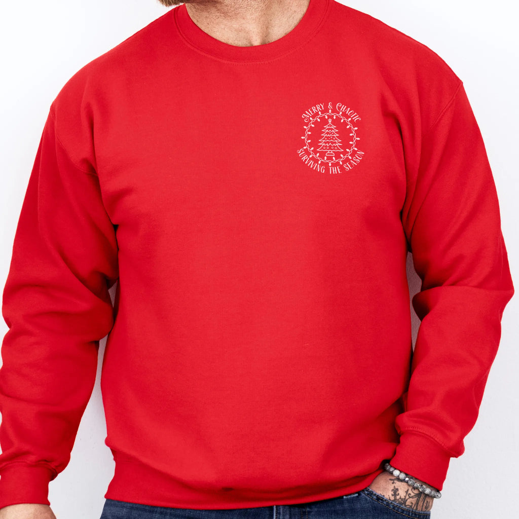Red men’s sweatshirt left chest badge text “Merry & Chaotic — Surviving the Season”