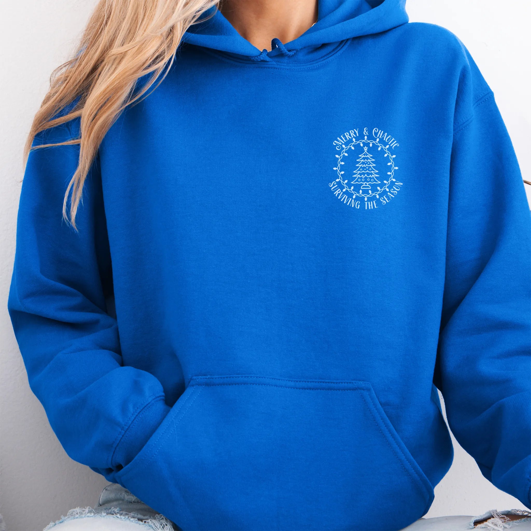 Royal women’s hoodie left chest badge text “Merry & Chaotic — Surviving the Season”