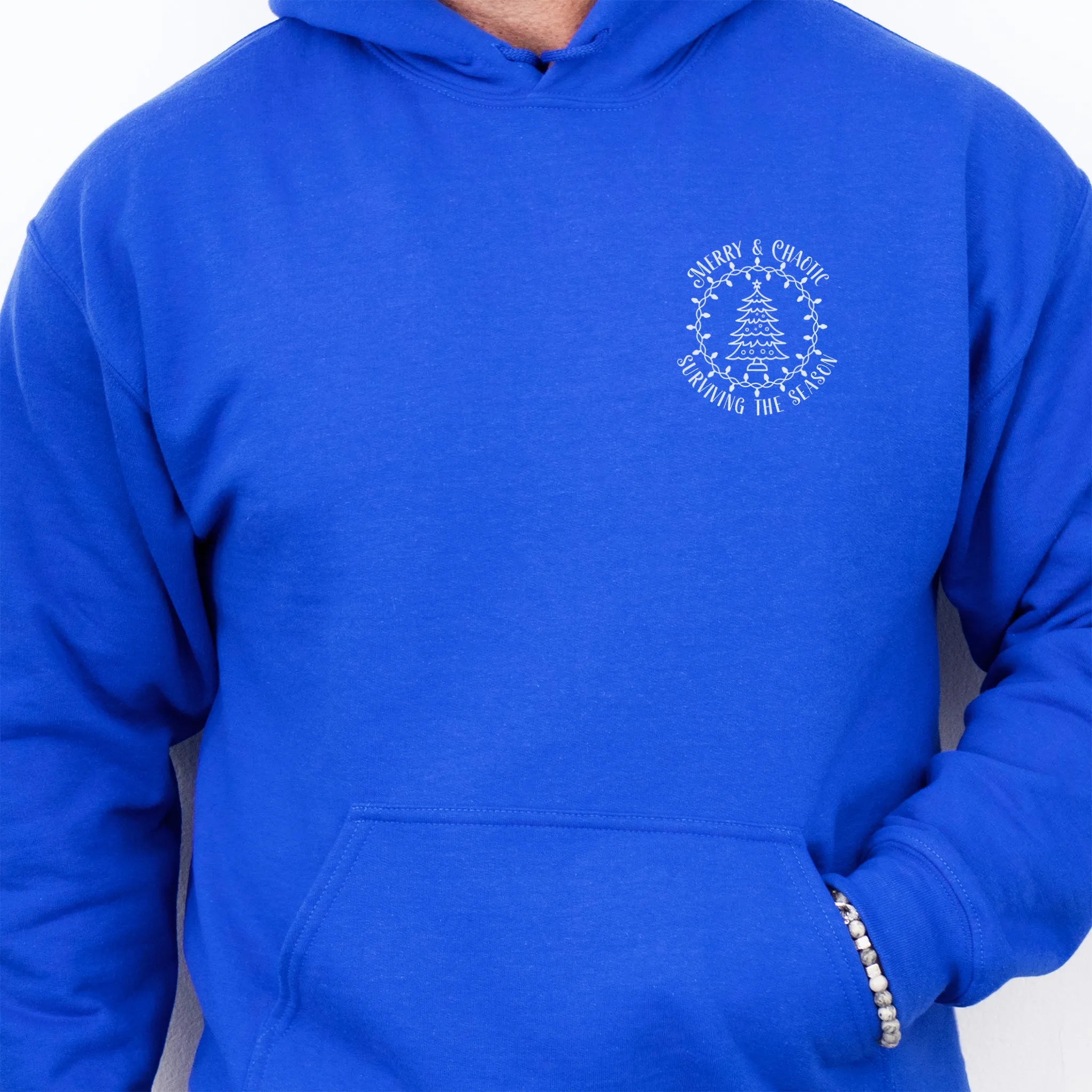 Royal men’s hoodie left chest badge text “Merry & Chaotic — Surviving the Season”