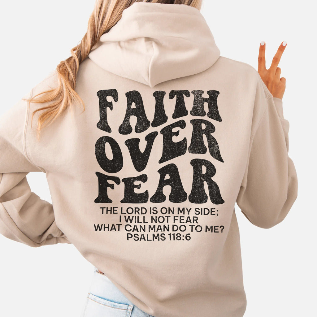 Sand Oakley June hoodie, large back lettering reads Faith Over Fear with supporting scripture lines, hood up, studio back view