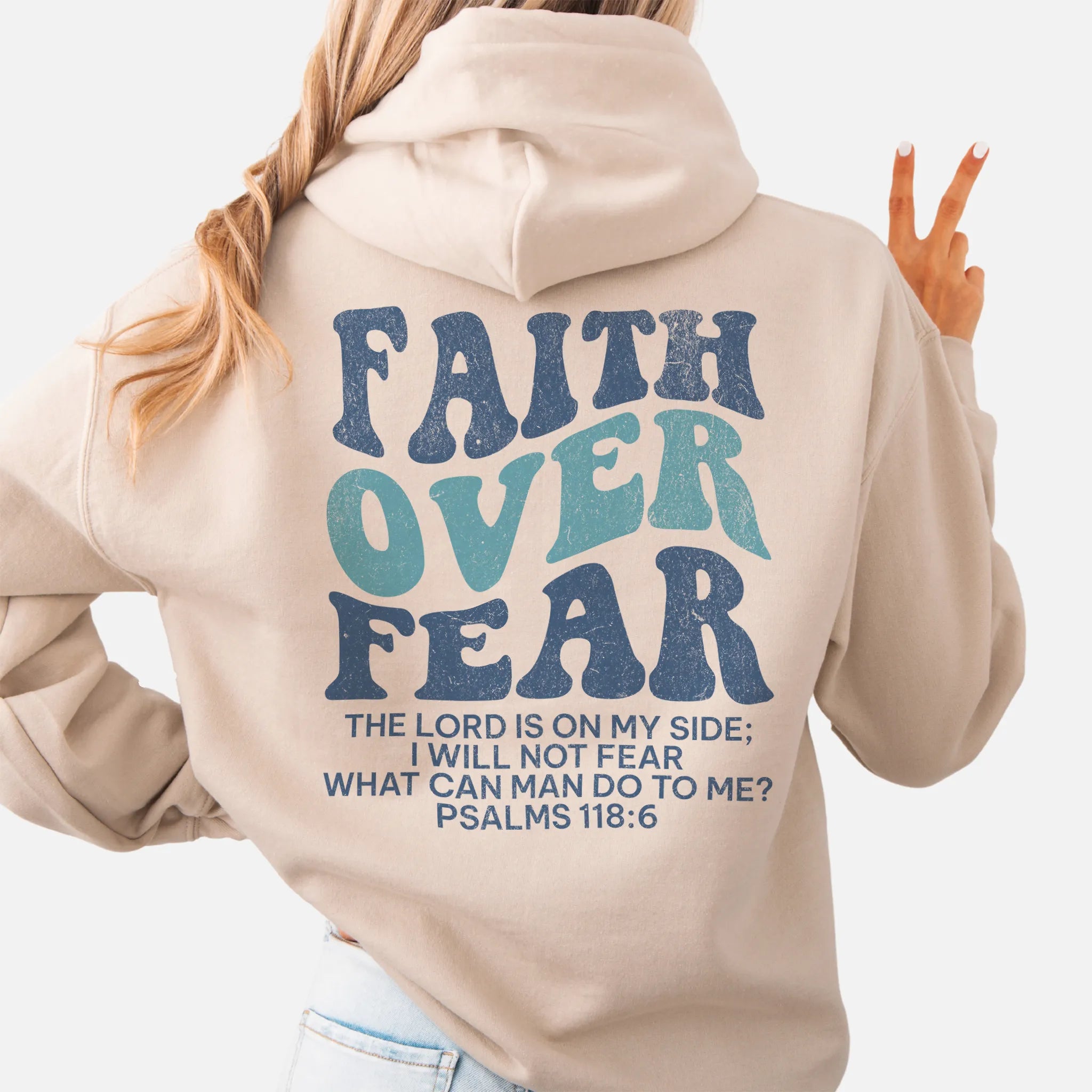 Sand Oakley June hoodie, large back lettering reads Faith Over Fear with supporting scripture lines, hood up, studio back view