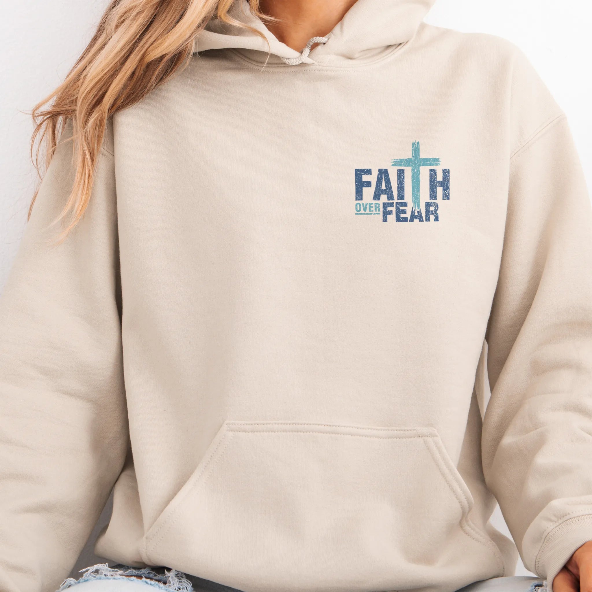 Sand Oakley June hoodie, left chest badge reads Faith Over Fear with small cross, kangaroo pocket and relaxed modern fit, studio front view