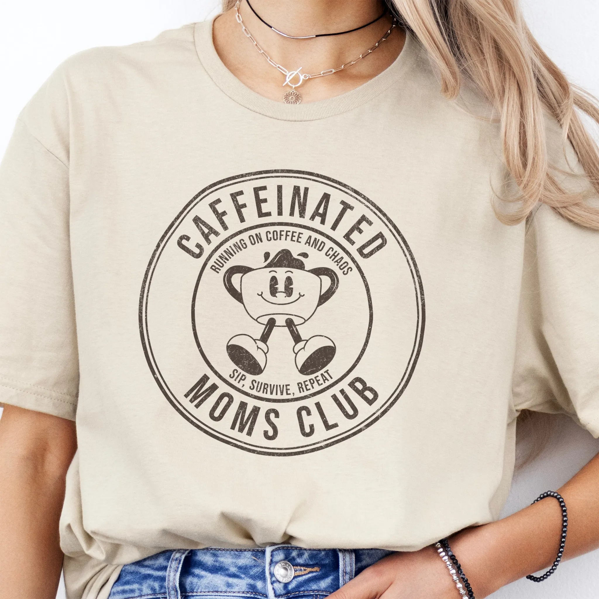 Sand Oakley June T Shirt front view large Caffeinated Moms Club circle badge coffee cup mascot text Running on Coffee and Chaos Sip Survive Repeat distressed