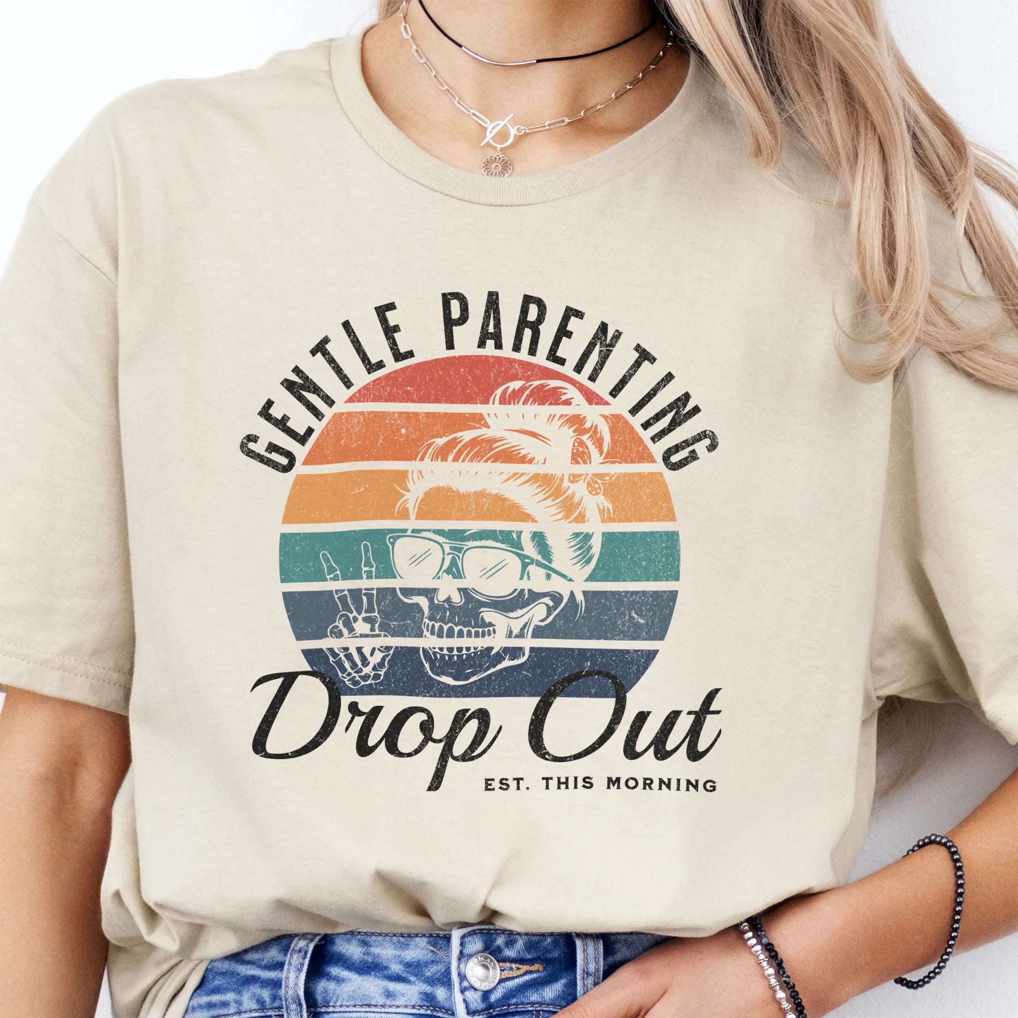 Sand Oakley June T Shirt front view Gentle Parenting Drop Out large chest graphic skull with messy bun sunglasses peace sign round retro stripe badge text Est This Morning distressed print