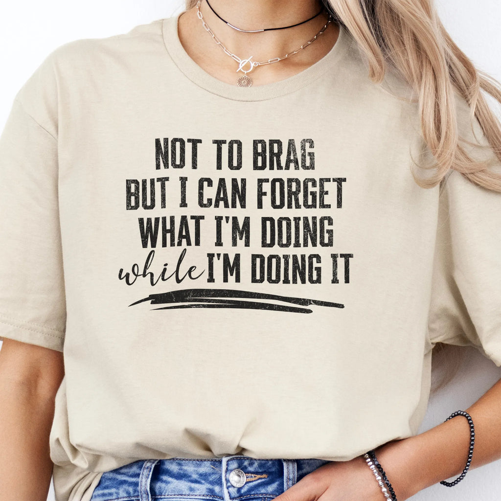 Sand Oakley June T Shirt front view large text Not To Brag But I Can Forget What I’m Doing While I’m Doing It underline distressed print