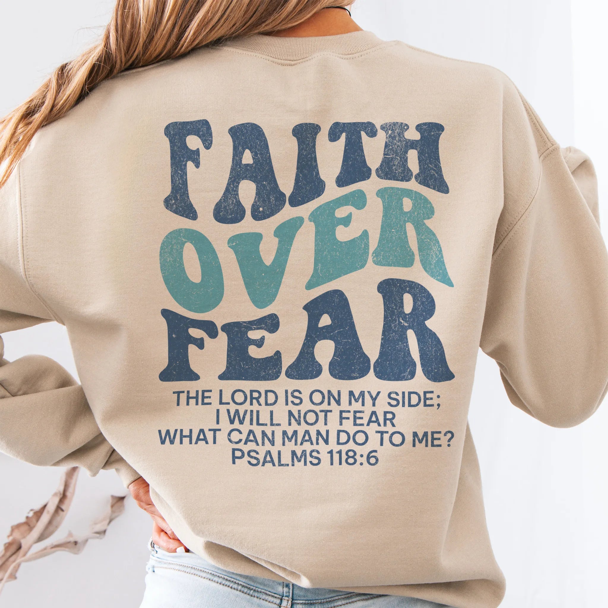 Sand Oakley June sweatshirt, large back lettering reads Faith Over Fear with supporting scripture lines, studio back view