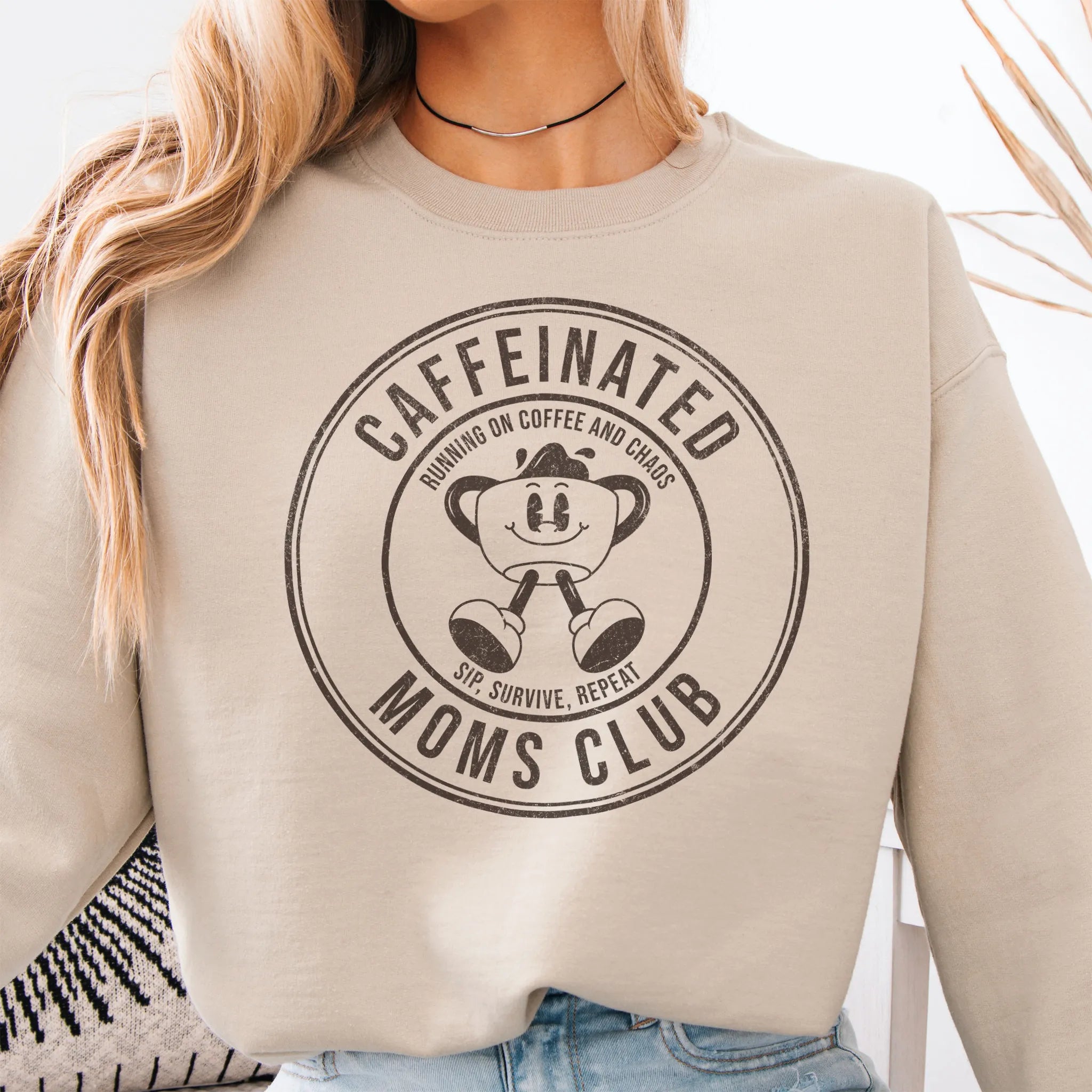 Sand Oakley June Sweatshirt front view large Caffeinated Moms Club circle badge coffee cup mascot text Running on Coffee and Chaos Sip Survive Repeat mono black ink distressed