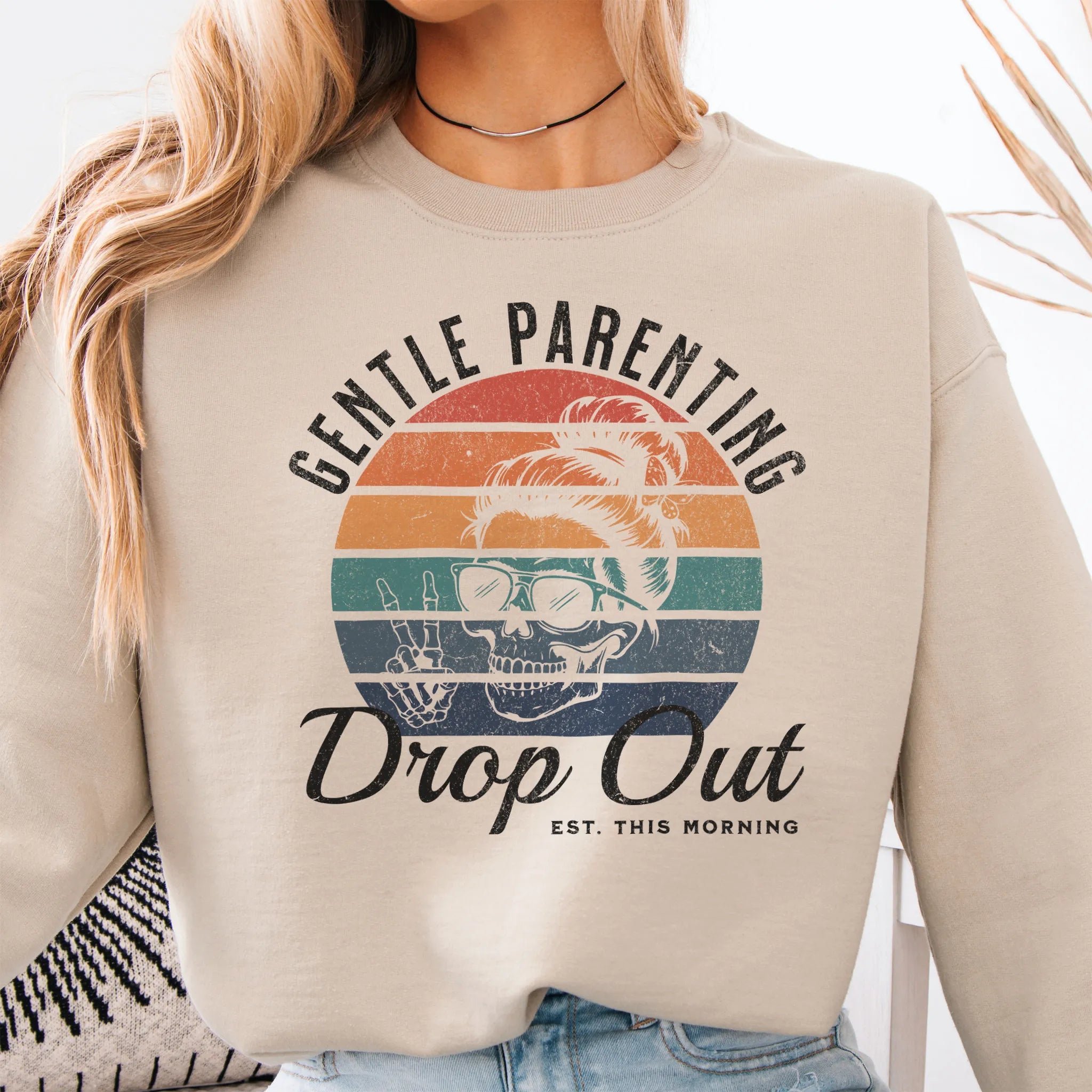 Sand Oakley June Sweatshirt front view Gentle Parenting Drop Out large chest graphic skull with messy bun peace sign round retro stripe badge text Est This Morning distressed print