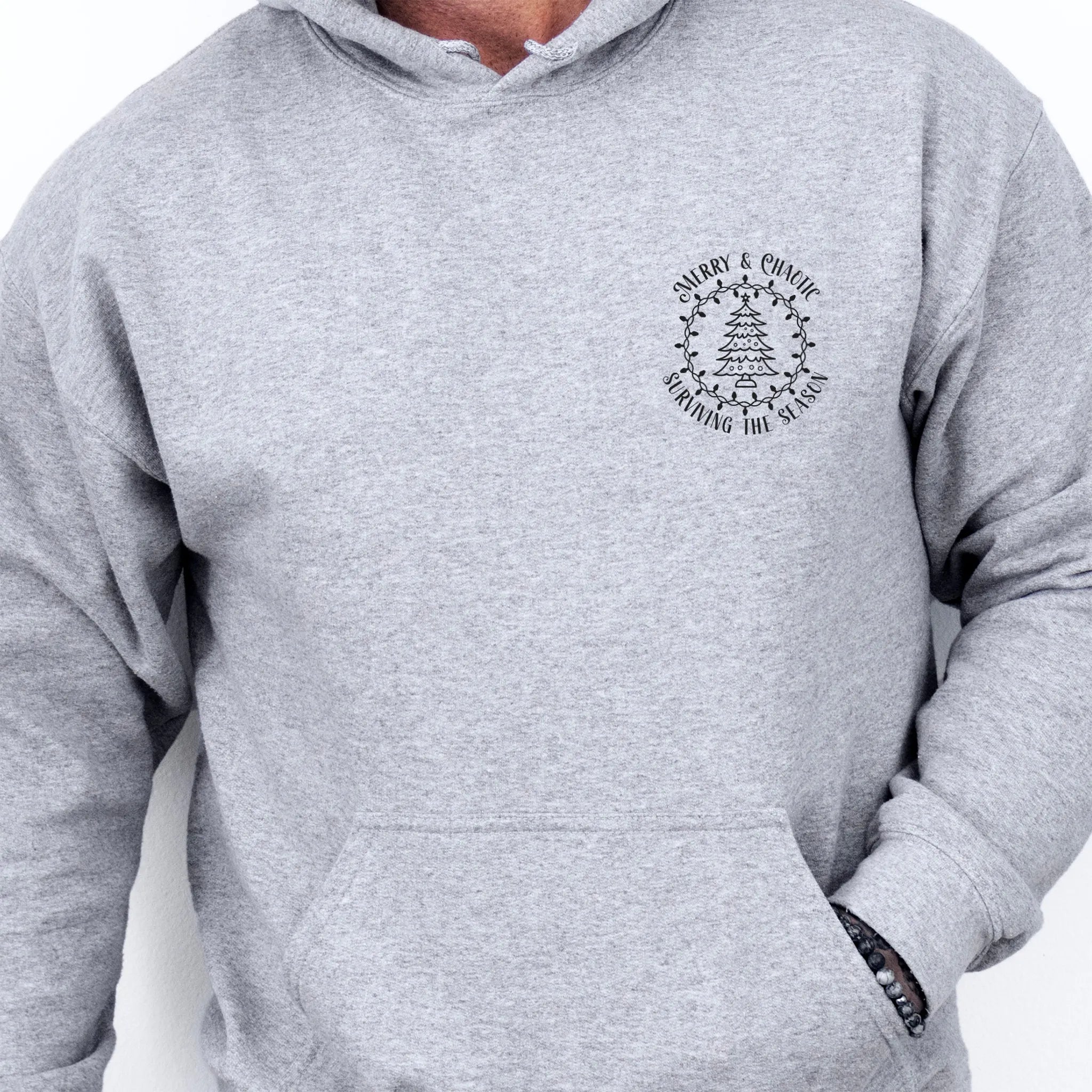 Sport Grey men’s hoodie left chest badge text “Merry & Chaotic — Surviving the Season”