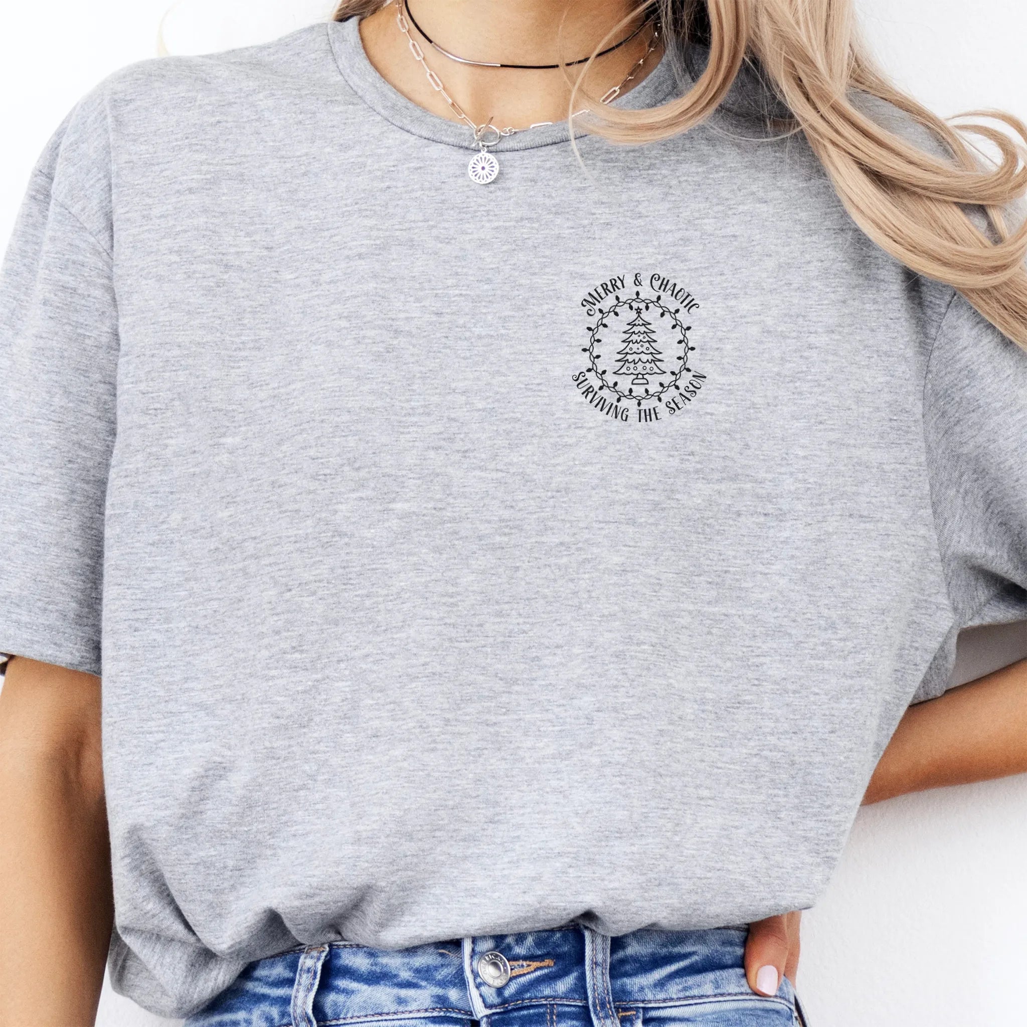 Sport Grey Oakley June tee left chest badge text “Merry & Chaotic — Surviving the Season” with Christmas tree