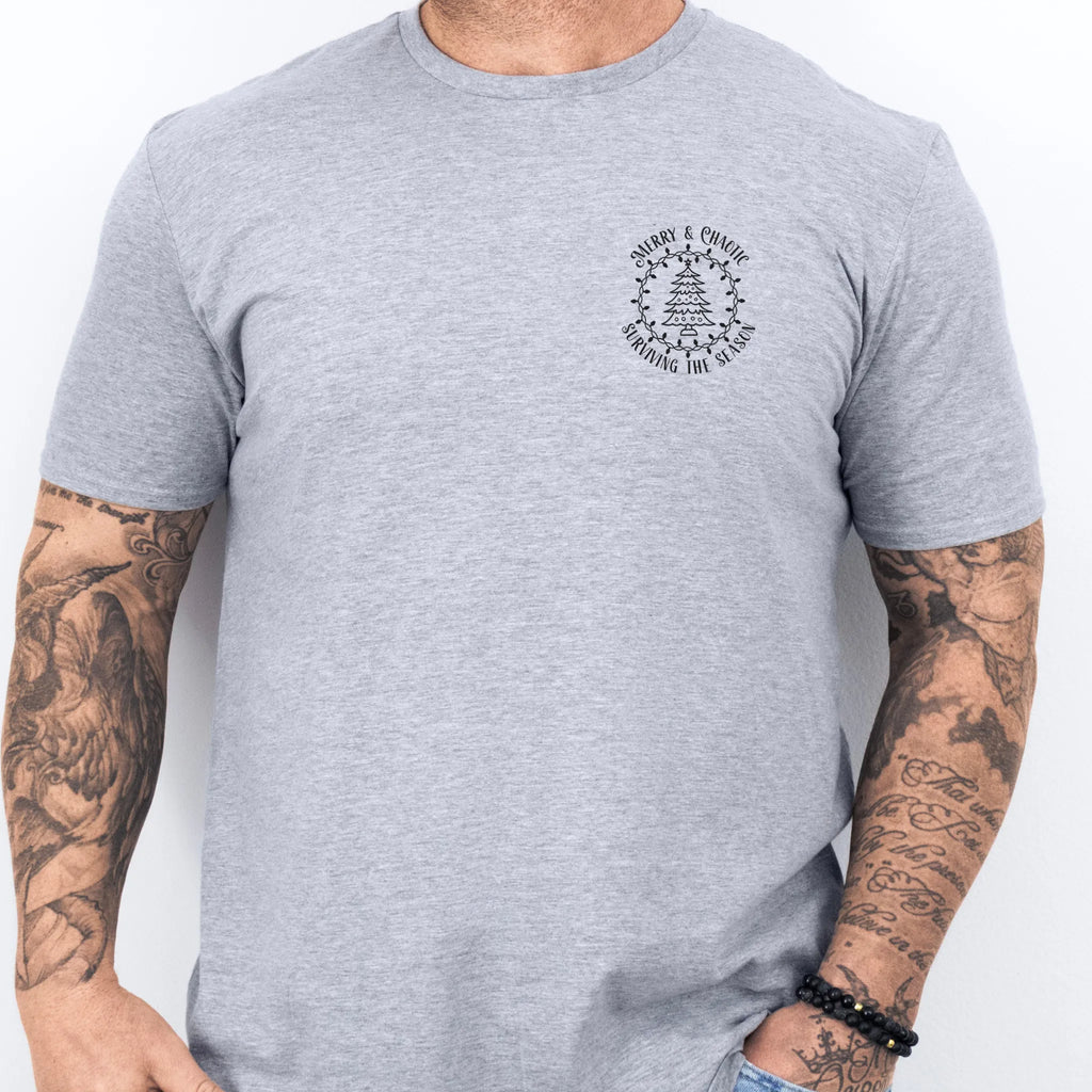 Sport Grey Oakley June tee left chest badge text “Merry & Chaotic — Surviving the Season” with Christmas tree